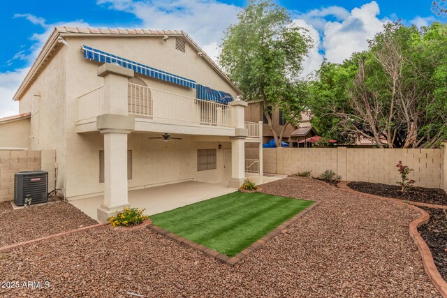 rear view of property featuring central AC unit, a ceiling fan, a fenced backyard, and stucco siding
