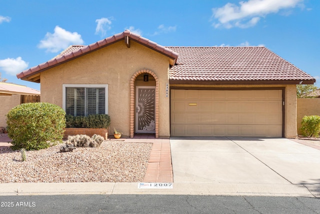 view of front of house with a tile roof, an attached garage, driveway, and stucco siding