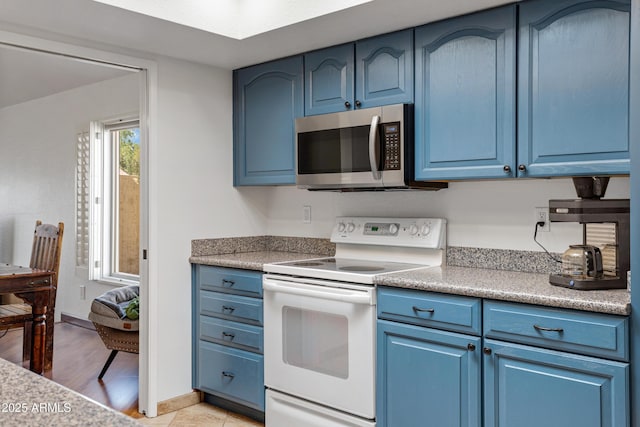 kitchen featuring electric range, light wood-style flooring, light countertops, stainless steel microwave, and blue cabinets