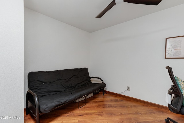 living area featuring light wood-style floors, baseboards, and ceiling fan