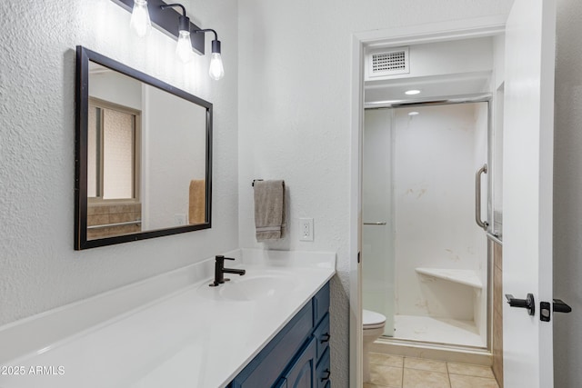 bathroom with vanity, visible vents, a stall shower, tile patterned flooring, and toilet