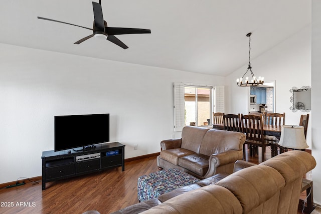 living area featuring ceiling fan with notable chandelier, vaulted ceiling, wood finished floors, and baseboards