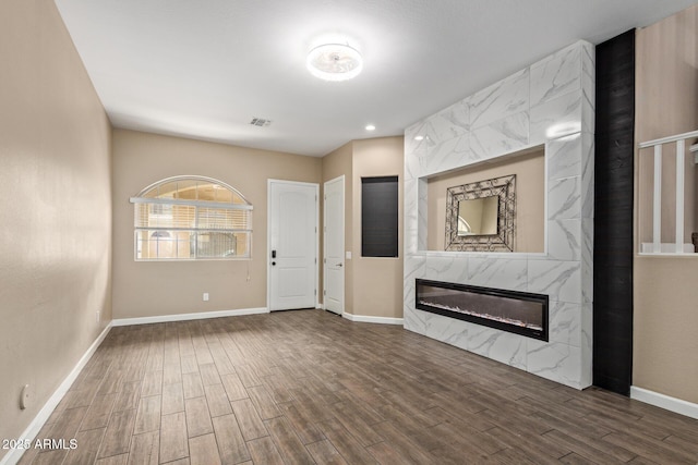 entryway featuring wood finished floors, a high end fireplace, and baseboards