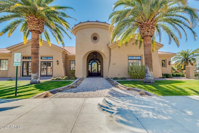 view of front of house featuring french doors, stucco siding, and a front lawn