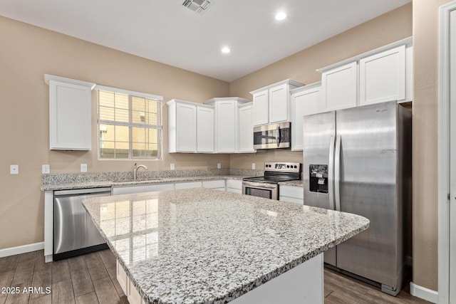 kitchen with stainless steel appliances, dark wood-style floors, baseboards, a sink, and white cabinetry
