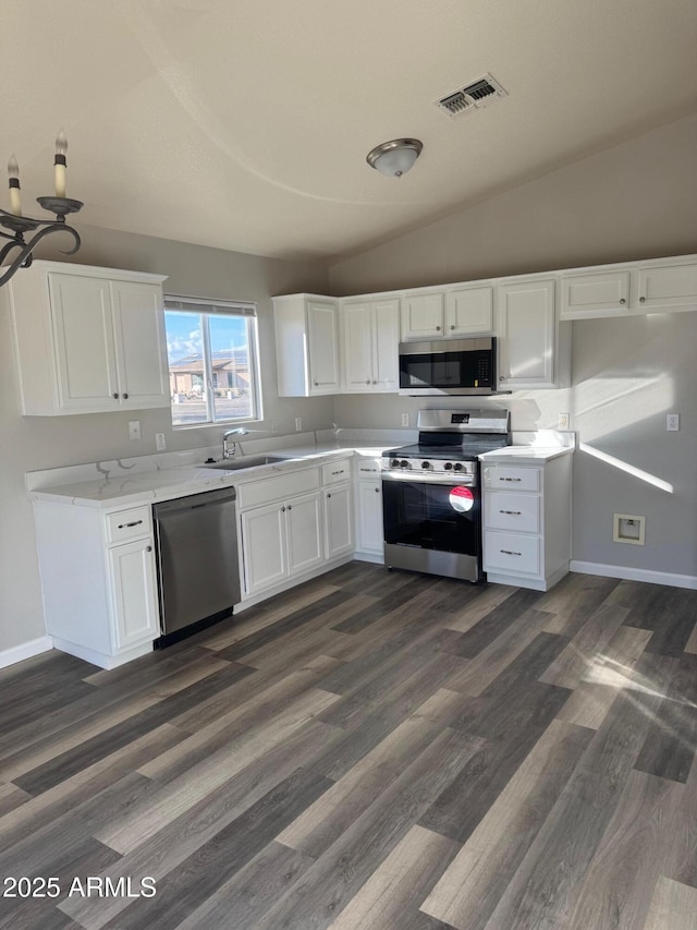 kitchen with sink, dark wood-type flooring, white cabinetry, stainless steel appliances, and vaulted ceiling