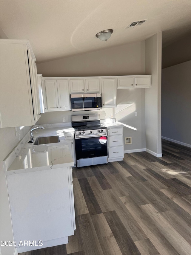 kitchen with dark hardwood / wood-style floors, white cabinetry, lofted ceiling, sink, and stainless steel appliances