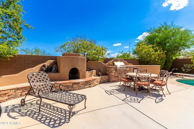 view of patio featuring exterior kitchen, grilling area, and an outdoor stone fireplace