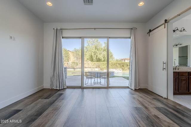 22709 S 202nd St, Queen Creek, AZ 85142 - empty room with a barn door, wood finished floors, baseboards, recessed lighting, and a sink