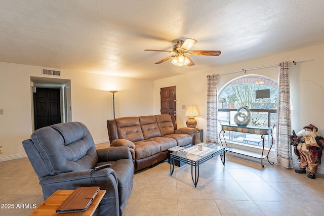 living room featuring ceiling fan, light tile patterned floors, and a textured ceiling