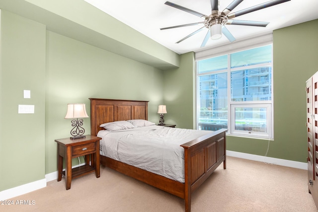 bedroom featuring ceiling fan, multiple windows, and light colored carpet