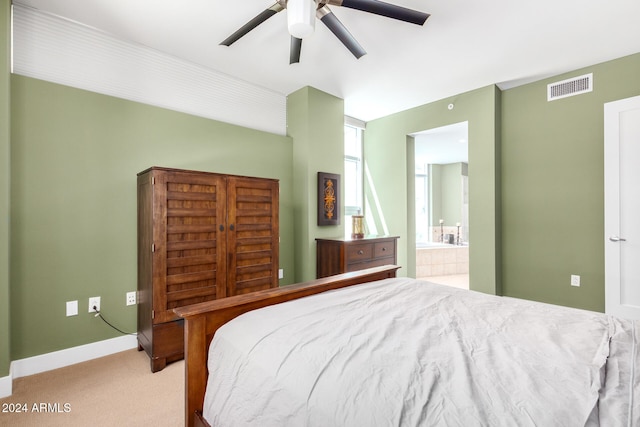 bedroom featuring ensuite bathroom, light carpet, and ceiling fan