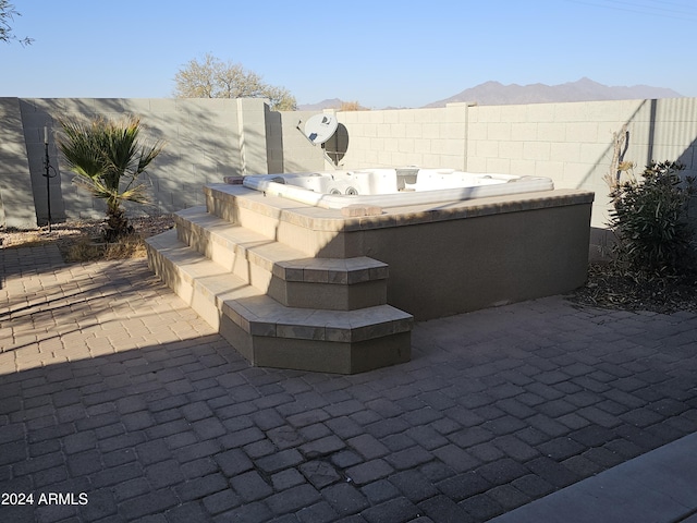 view of patio with a mountain view and a hot tub