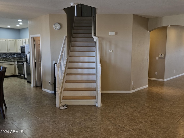 stairway featuring a textured ceiling