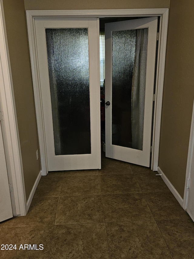 hallway featuring dark tile patterned flooring and french doors