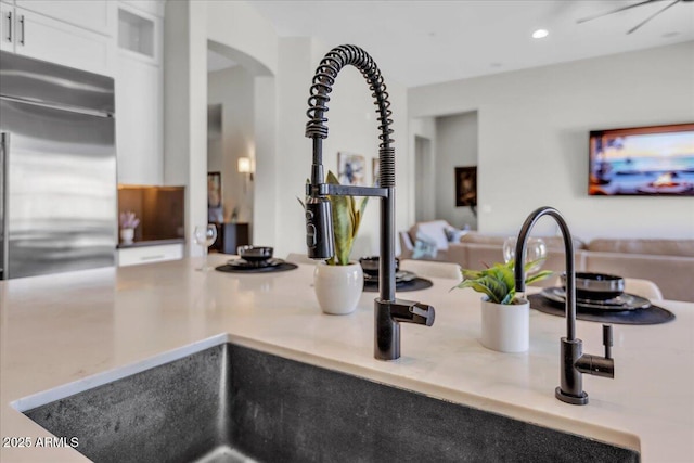 interior details with glass insert cabinets, light stone countertops, recessed lighting, arched walkways, and white cabinetry