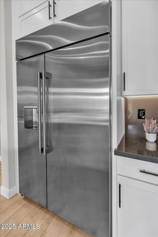 interior details featuring white cabinets, light wood-type flooring, and built in fridge