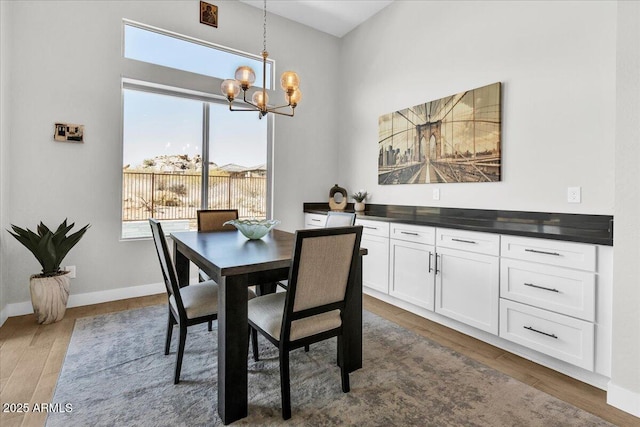 dining room featuring a notable chandelier, baseboards, and wood finished floors