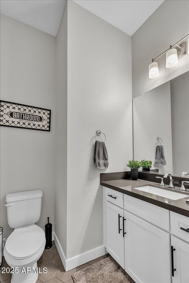 half bath featuring tile patterned floors, baseboards, toilet, and vanity