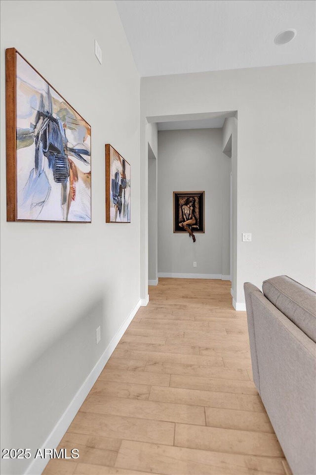 corridor featuring light wood finished floors and baseboards