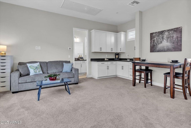 living area featuring visible vents, baseboards, and light colored carpet