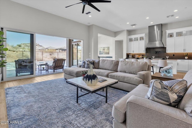 living area with light wood-style flooring, visible vents, and ceiling fan