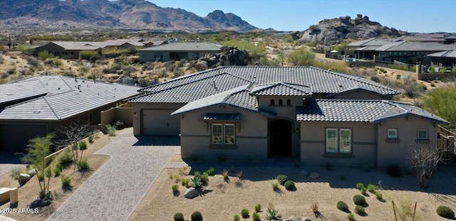 view of front of house featuring stucco siding, a mountain view, a tile roof, and decorative driveway