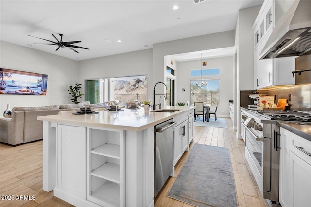 kitchen with a center island with sink, a sink, decorative backsplash, stainless steel appliances, and under cabinet range hood