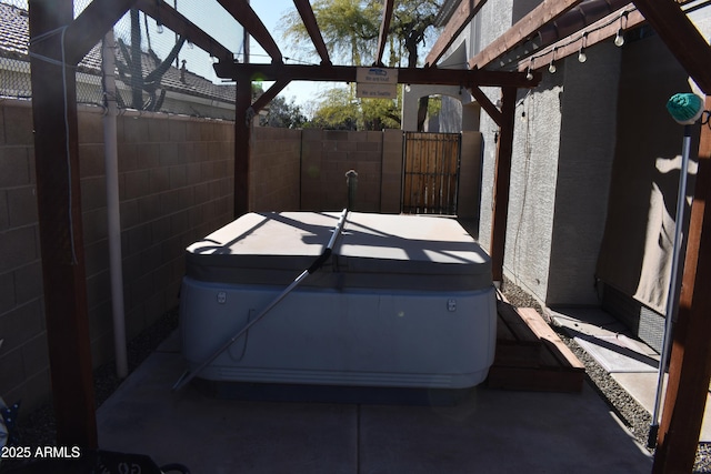 view of patio with glass enclosure, fence, and a hot tub