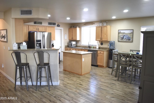 kitchen featuring a peninsula, light wood-type flooring, visible vents, and stainless steel appliances