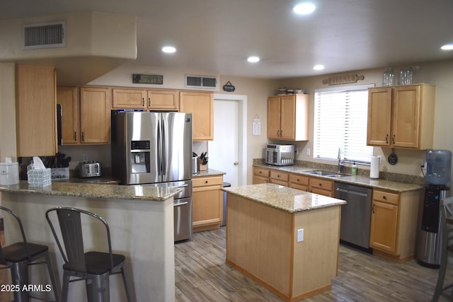 kitchen with visible vents, a peninsula, stainless steel appliances, and a sink