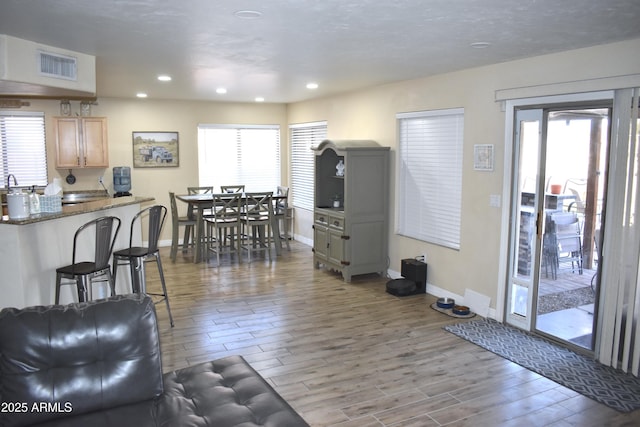 living area with recessed lighting, wood finished floors, visible vents, and baseboards