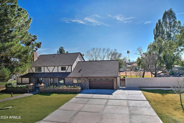 tudor-style house featuring a garage and a front lawn