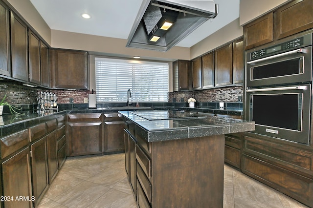 kitchen featuring double oven, dark brown cabinets, a kitchen island, and extractor fan