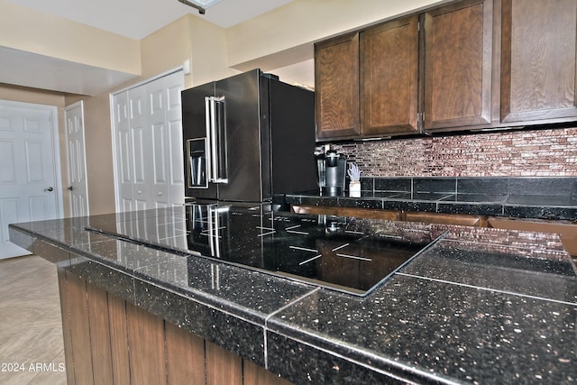 kitchen featuring black appliances, dark brown cabinetry, light tile patterned floors, and backsplash