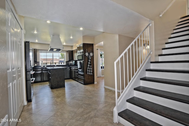 interior space featuring island exhaust hood, dark brown cabinetry, sink, and a kitchen island