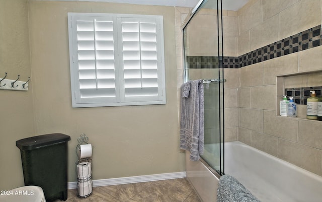 bathroom featuring tile patterned flooring, enclosed tub / shower combo, and toilet