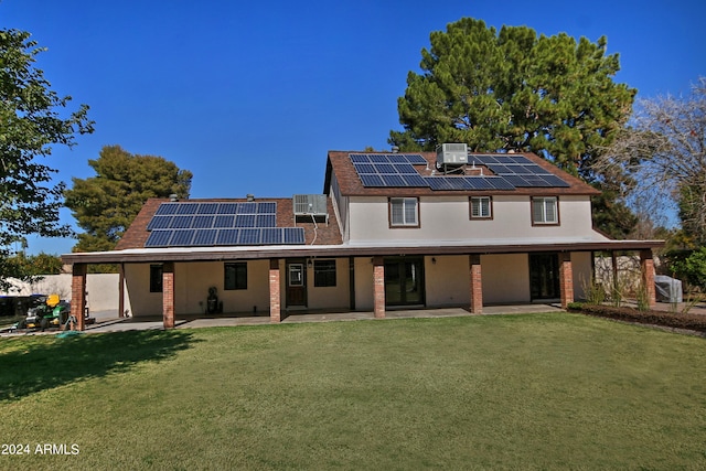 back of property with solar panels, a patio, cooling unit, and a lawn