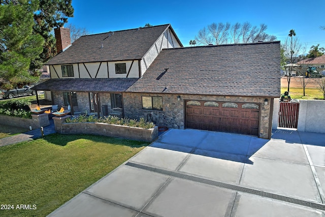 tudor home with a garage and a front yard