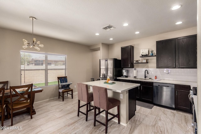 kitchen featuring sink, a breakfast bar area, stainless steel appliances, a kitchen island, and decorative light fixtures