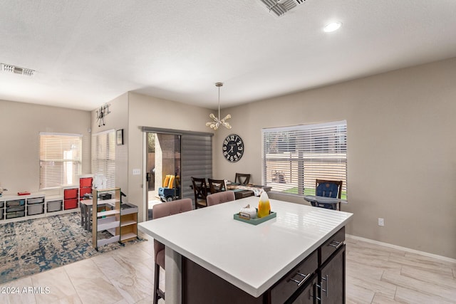 kitchen featuring decorative light fixtures, plenty of natural light, a center island, and a textured ceiling