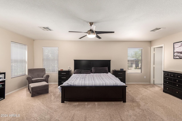 bedroom with ceiling fan, carpet, and a textured ceiling