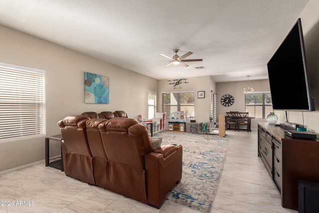 living room with plenty of natural light and ceiling fan with notable chandelier