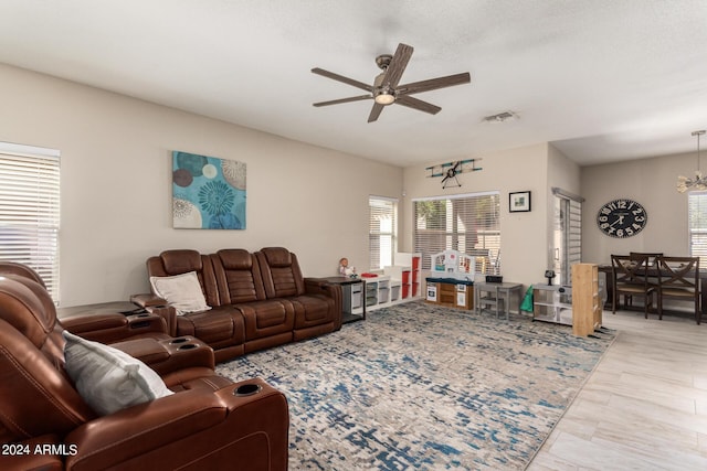 living room with ceiling fan with notable chandelier and a textured ceiling