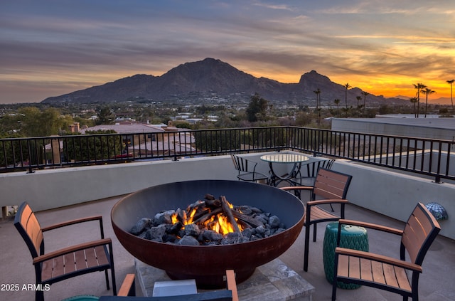 patio terrace at dusk featuring a mountain view and a fire pit