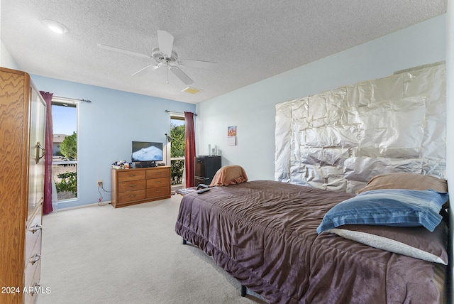 carpeted bedroom featuring ceiling fan and a textured ceiling