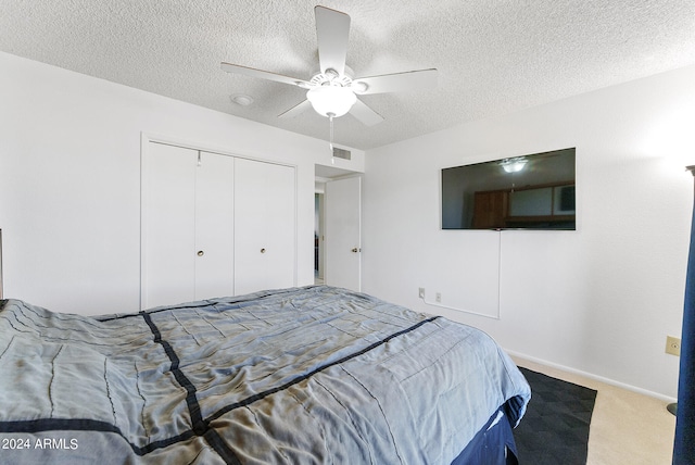 carpeted bedroom featuring a closet, ceiling fan, and a textured ceiling