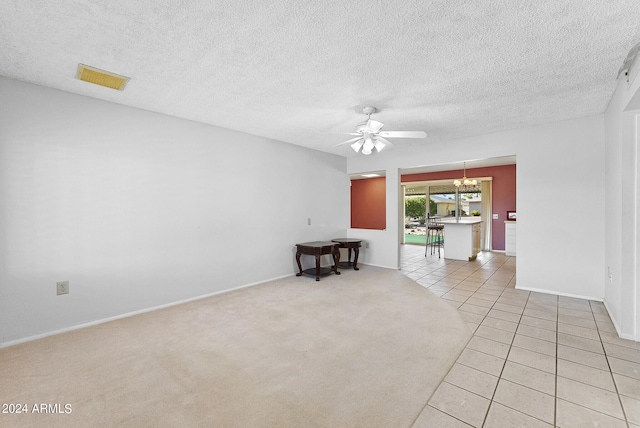 spare room featuring a textured ceiling, ceiling fan with notable chandelier, and light tile patterned floors