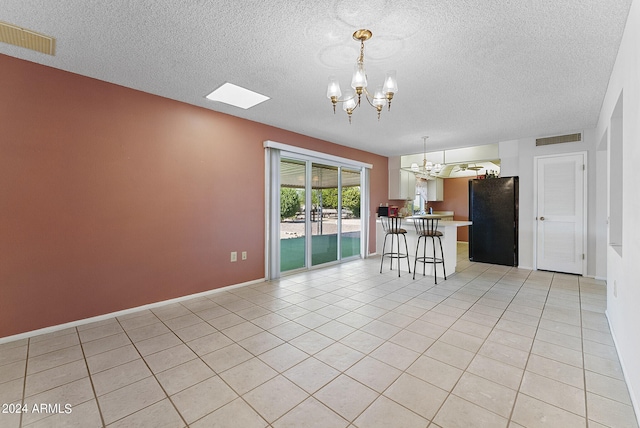 unfurnished room with a notable chandelier, a textured ceiling, and light tile patterned flooring