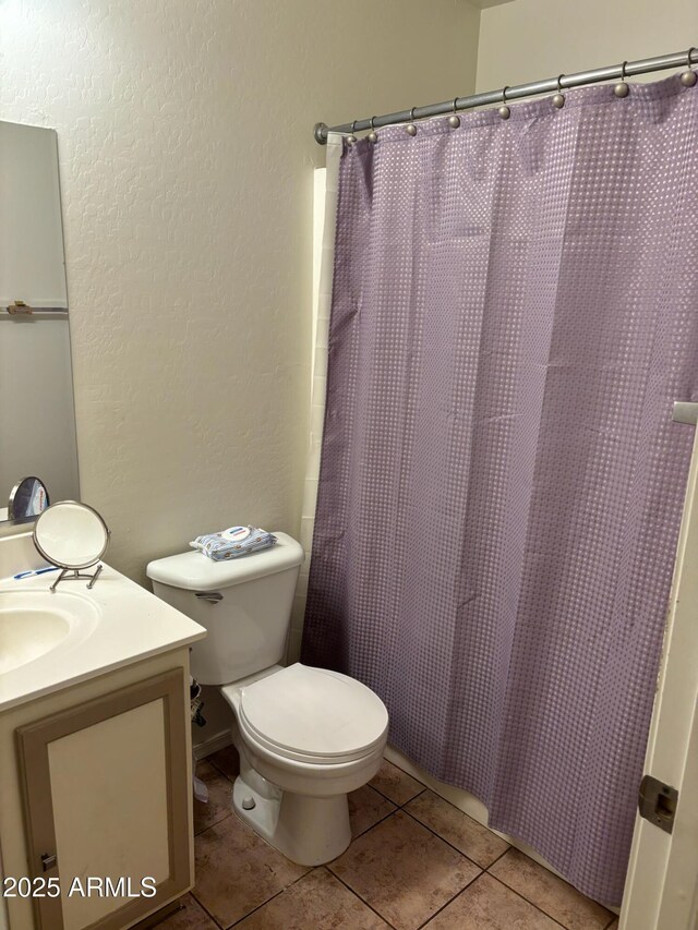 full bathroom featuring a textured wall, toilet, vanity, a shower with curtain, and tile patterned floors